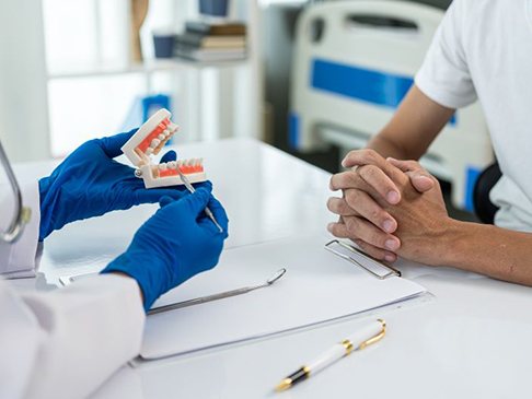 Dentist and patient sitting at desk, discussing treatment