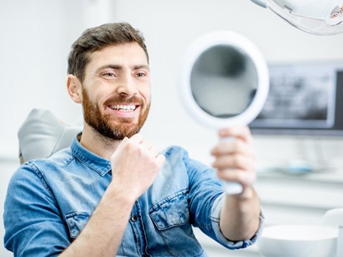 Man smiling at reflection in dentist's mirror