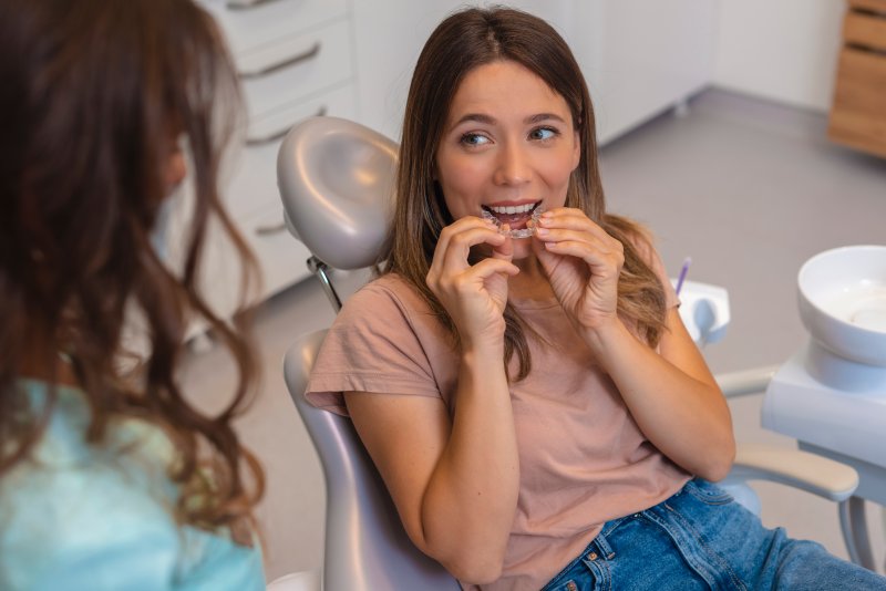 A woman inserting her clear aligner at a dentist’s office